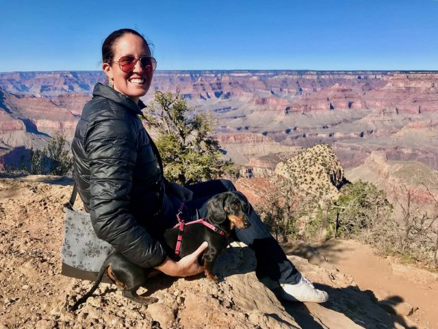 Sitting with dog next to Grand Canyon